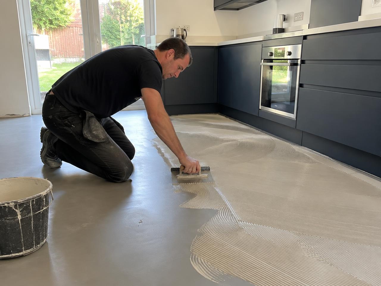 A fitter spreading adhesive with a notched trowel